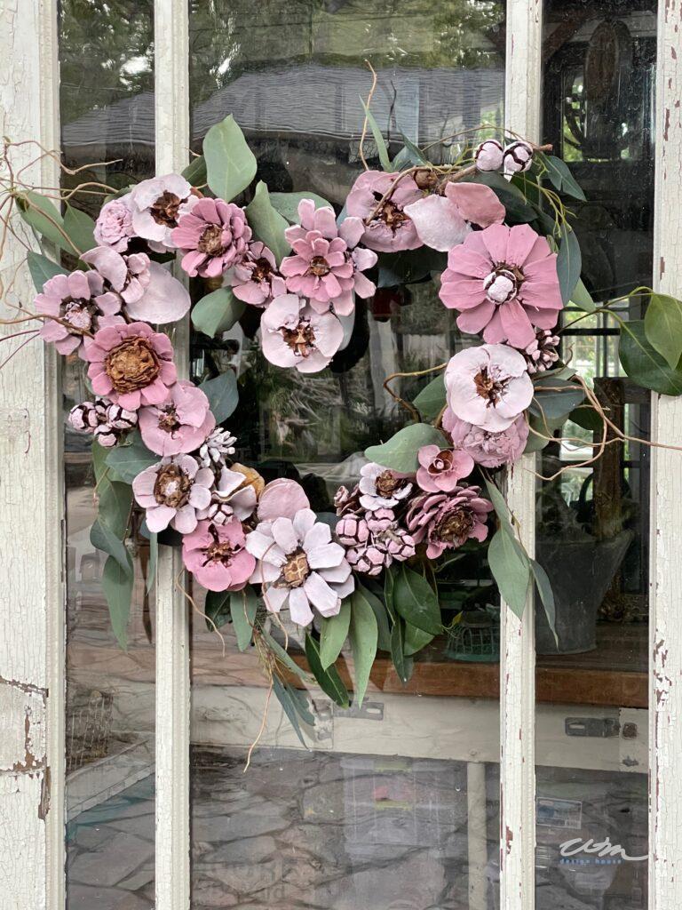 a wreath in the shape of a heart made out of cut pinecones to look like flowers. The pinecones are painted pink 