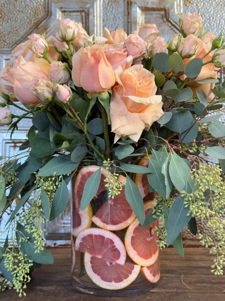 grapefruit flower arranging.Vase filled with grapefruit slices then filled with apricot roses. 