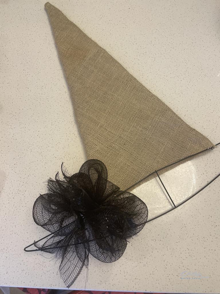 Adding black mesh bows to the brim of the wire witch's hat wreath form to make a DIY Halloween wreath
