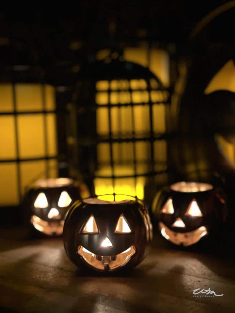 DIY Halloween Decor lanterns made from miniature plastic pumpkins lit up at night with a battery operated tea light