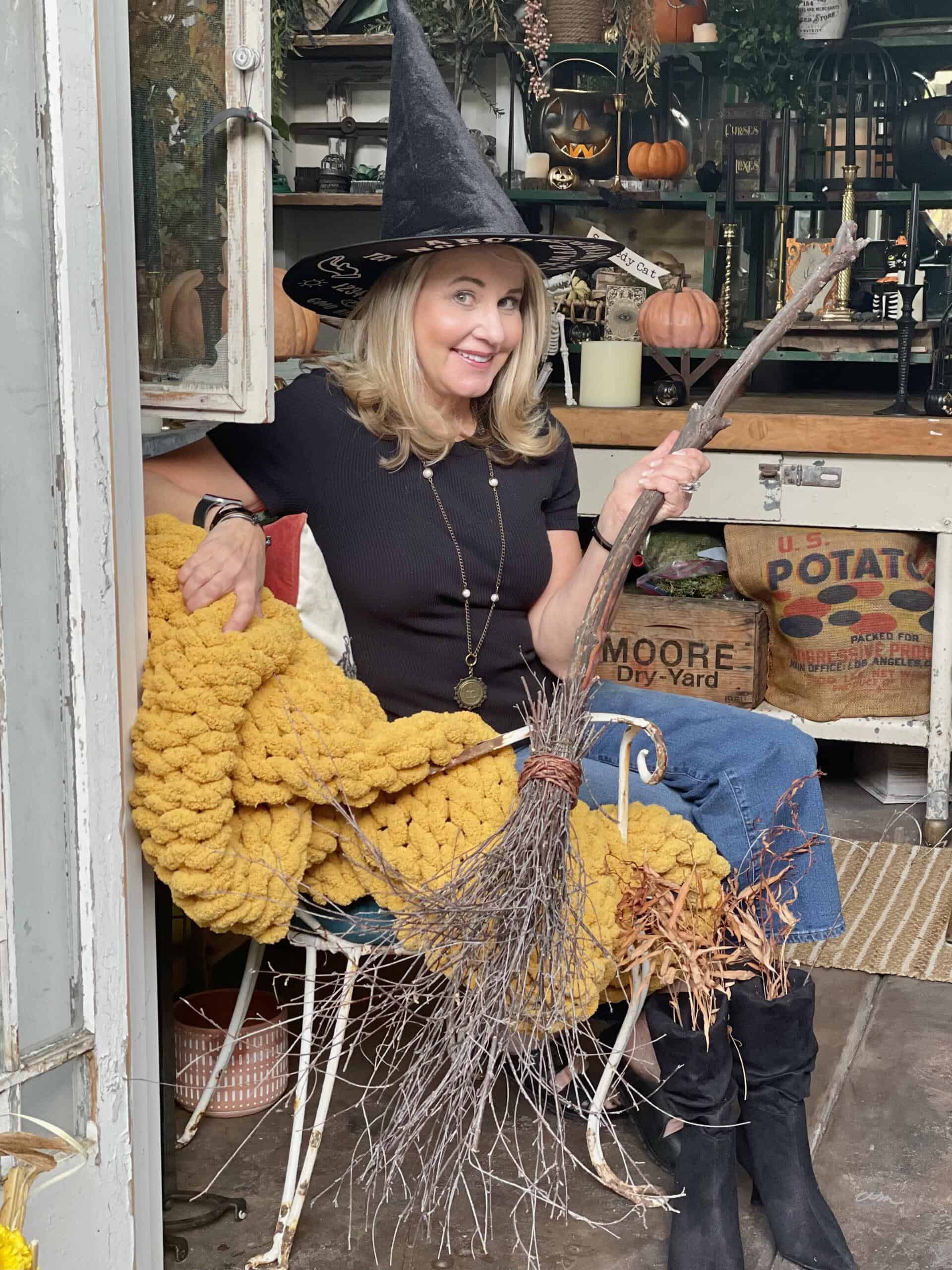 Wendy in front of the she shed holding a DIY Halloween Decor witches broom