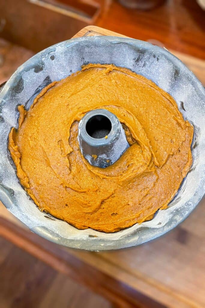 Cake batter is poured into a bundt cake pan before baking. 