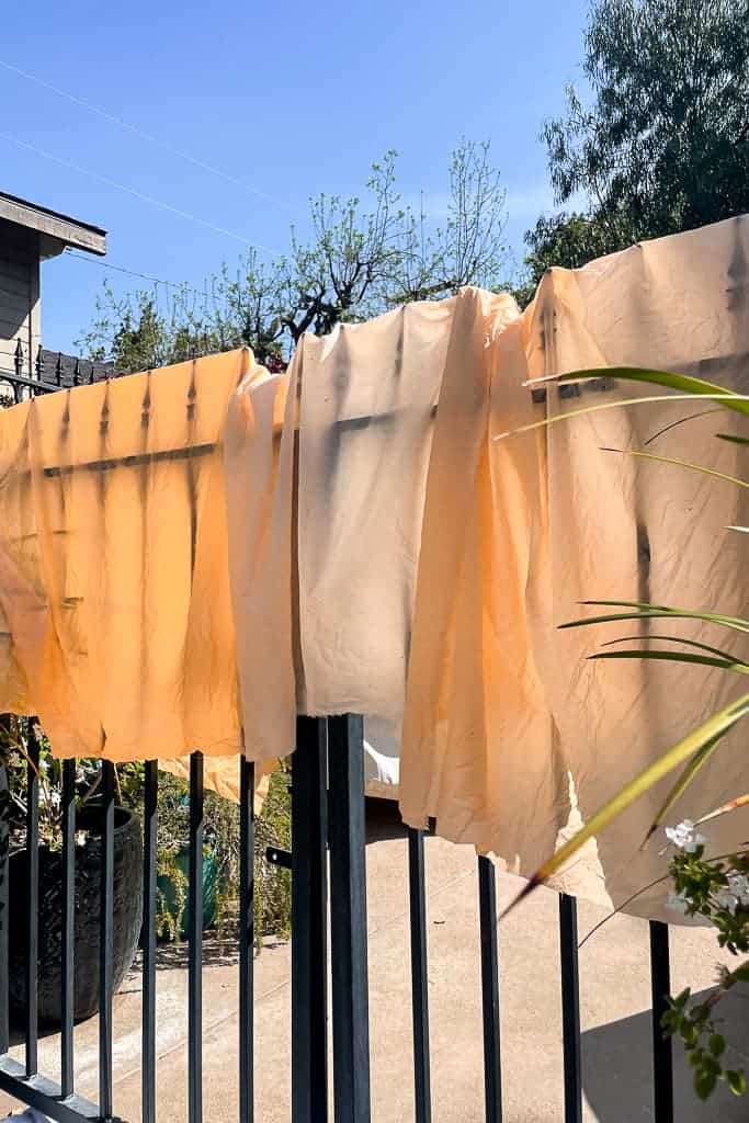 Fabric hanging to dry outside after being dyed in a natural carrot dye. 