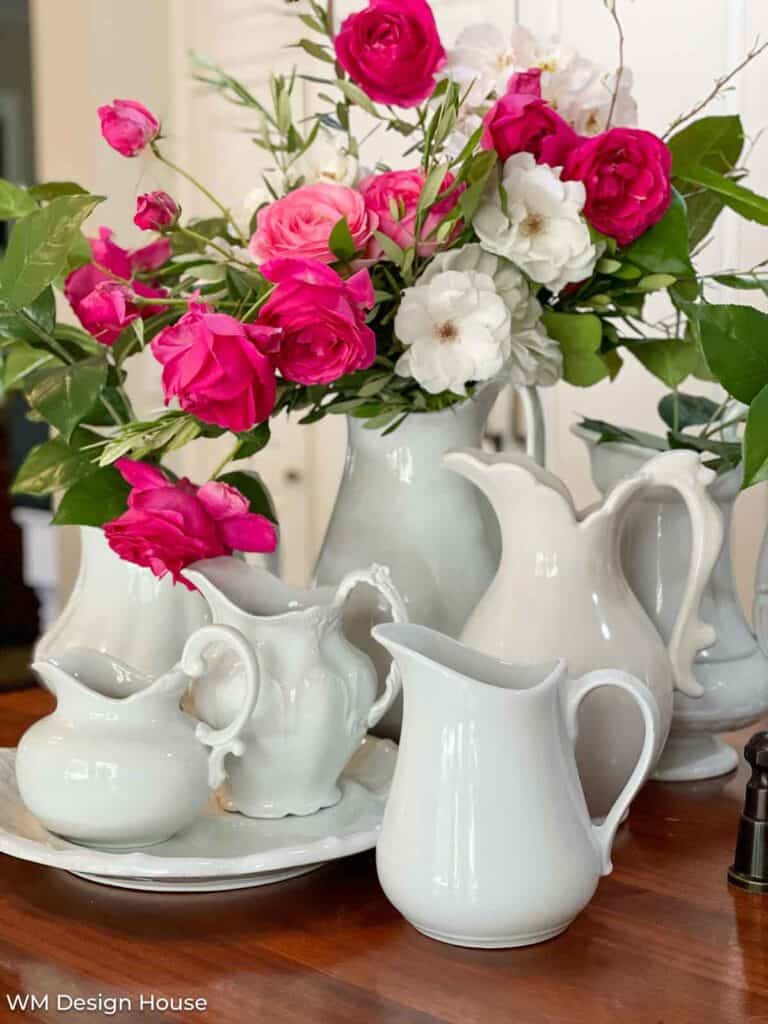 assortment of pink roses in white ironstone pitchers 