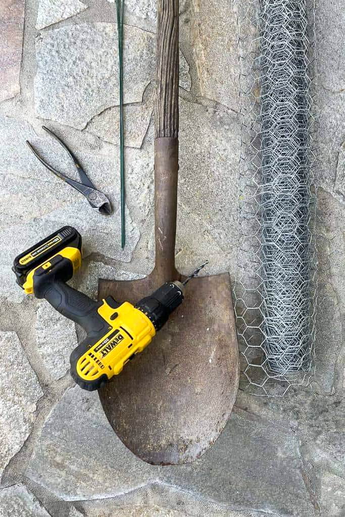 This is an image of a shovel, chicken wire, wire cutters, a drill, and wire, all needed to make a shovel planter. 