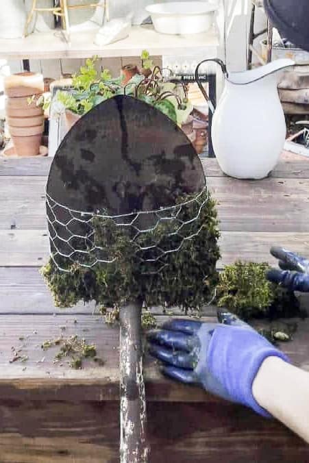 I am adding wet moss to a basket attached to a shovel. 