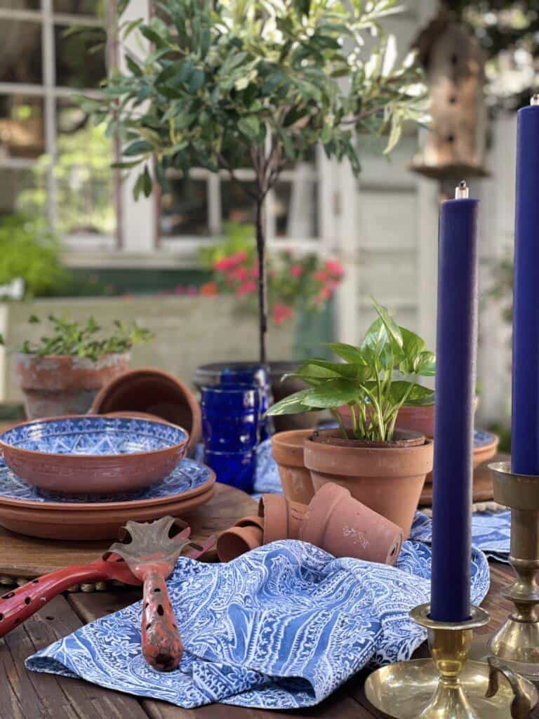 Distressed terracotta pots displayed on a table centerpiece with blue decor and old garden tools