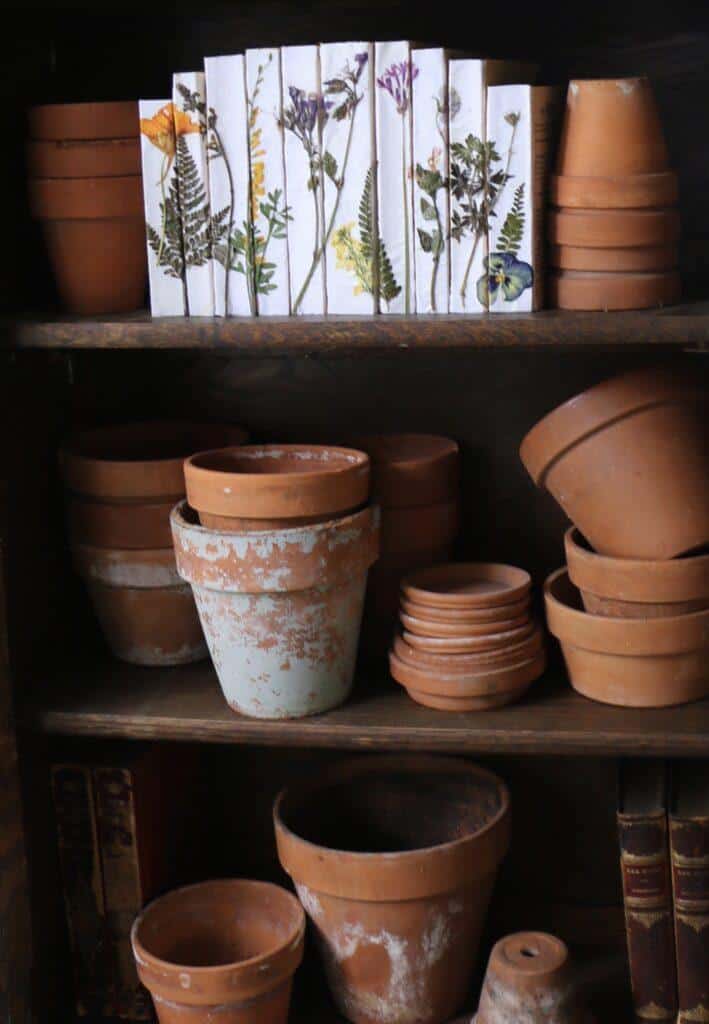 distressed vintage terracotta pots displayed on a shelf with spring decor and vintage books