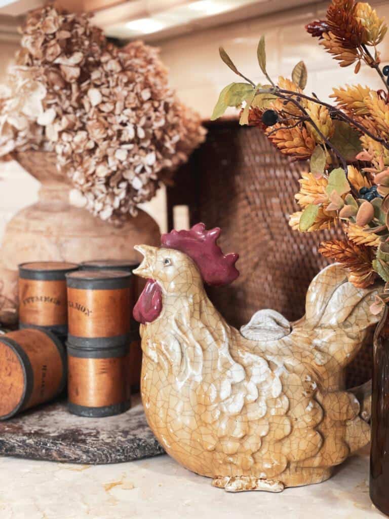 A fall vignette in the kitchen with a chicken, old spice jars and some fall foliage. 