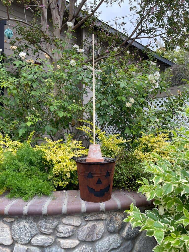 Rusty pumpkin bucket with clay pot on top of soil 
