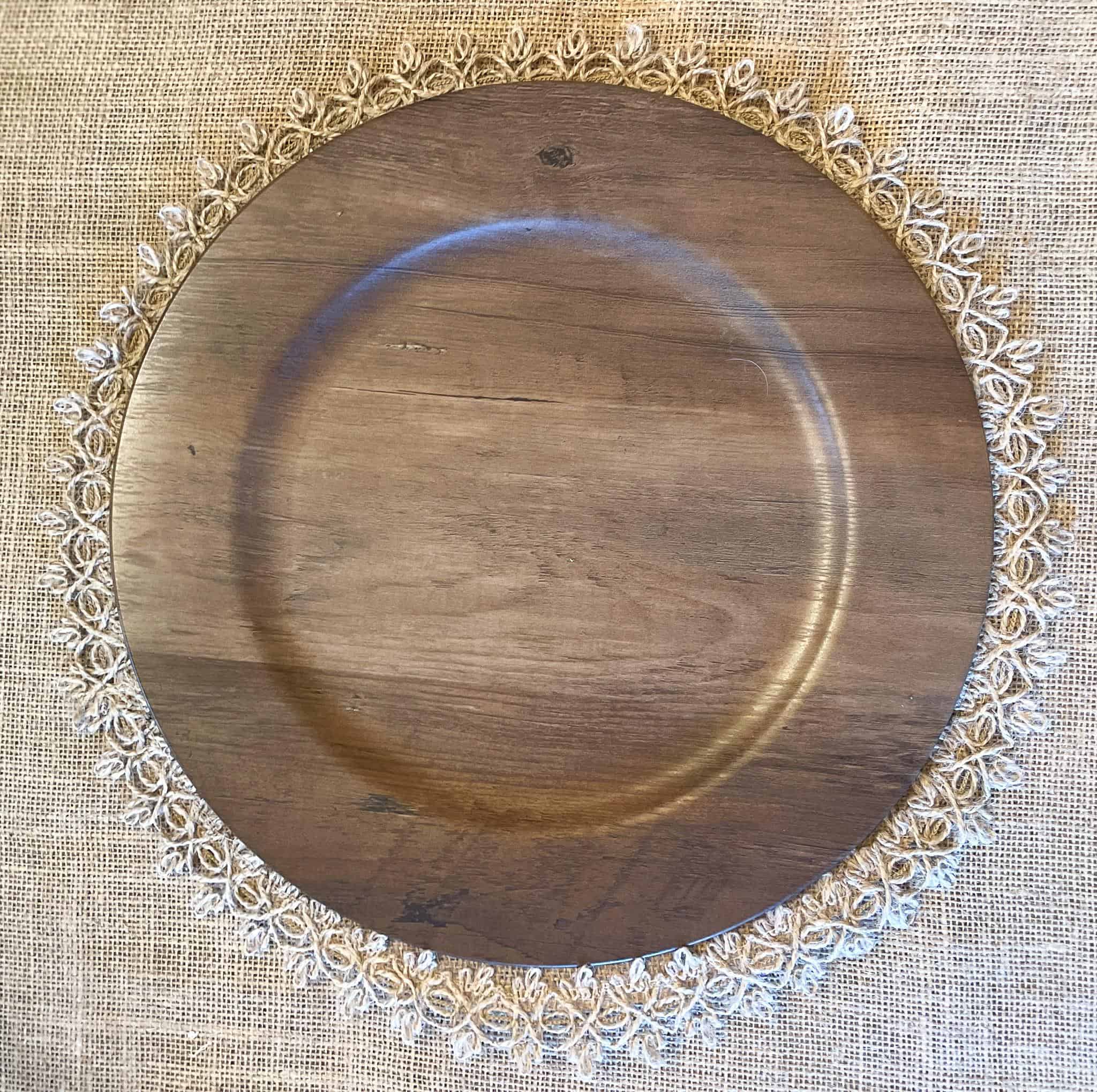 wooden charger plate being set for a place setting on a fall tablescape