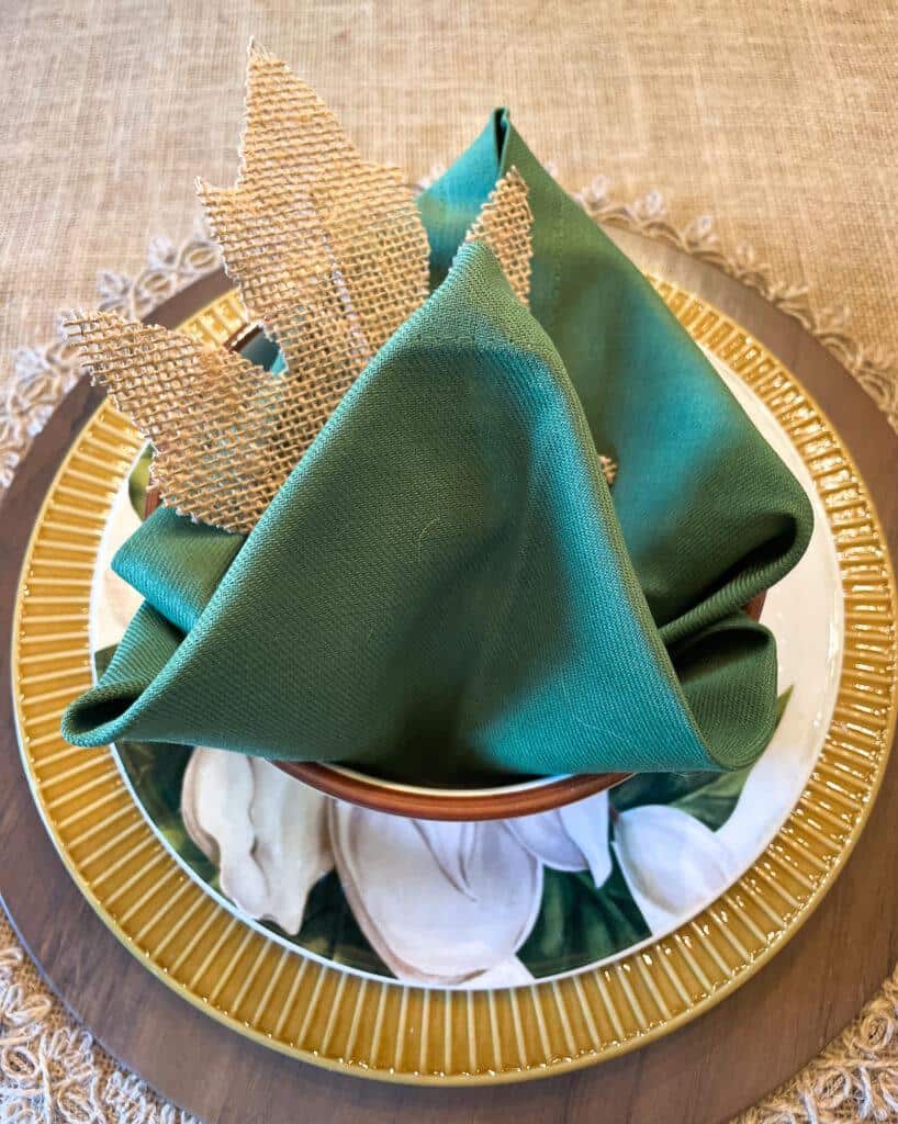 fall table setting with green napkin and burlap leaf