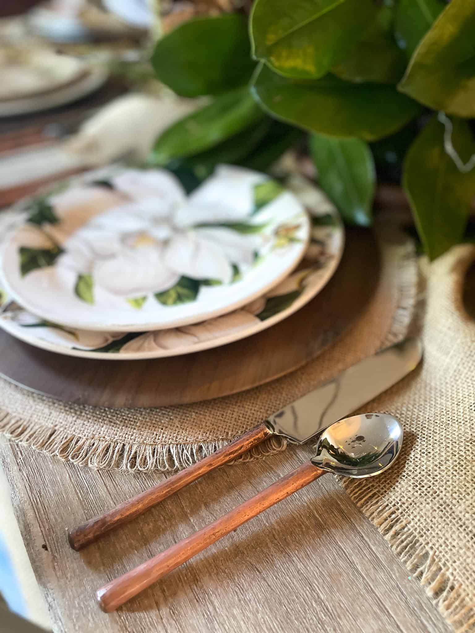 close-up view of mangolia dishes and silverware for a rustic table setting