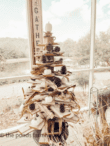A rustic wooden Christmas tree adorned with small white pumpkins and pinecones stands beside a vertical sign reading "Gather." The backdrop showcases trees and a pond through a large window. This scenic setup is part of the Fabulous Friday Link Party 9.30.22, photo by "the ponds farmh.
