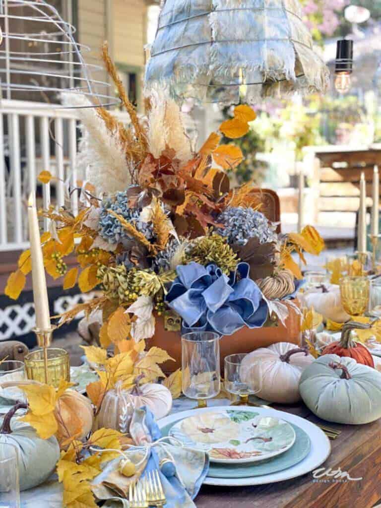 A beautiful fall tablescape that is outdoors  in hues of blues and golds 