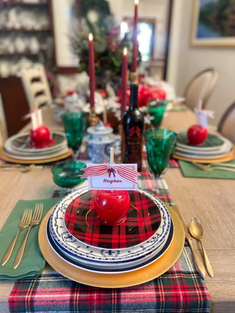 A Christmas dinner table set with red candied apples for place card holders.