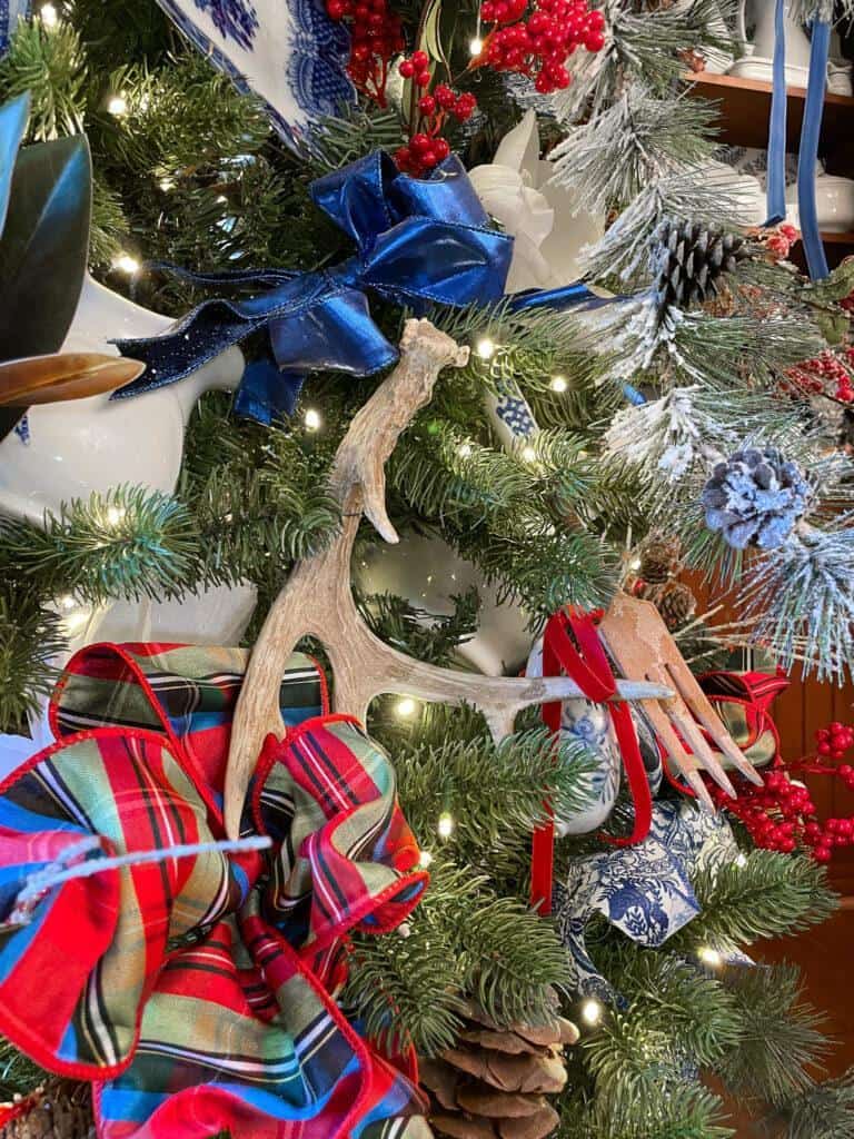 Antlers on a Christmas tree with blue and plaid ribbons.