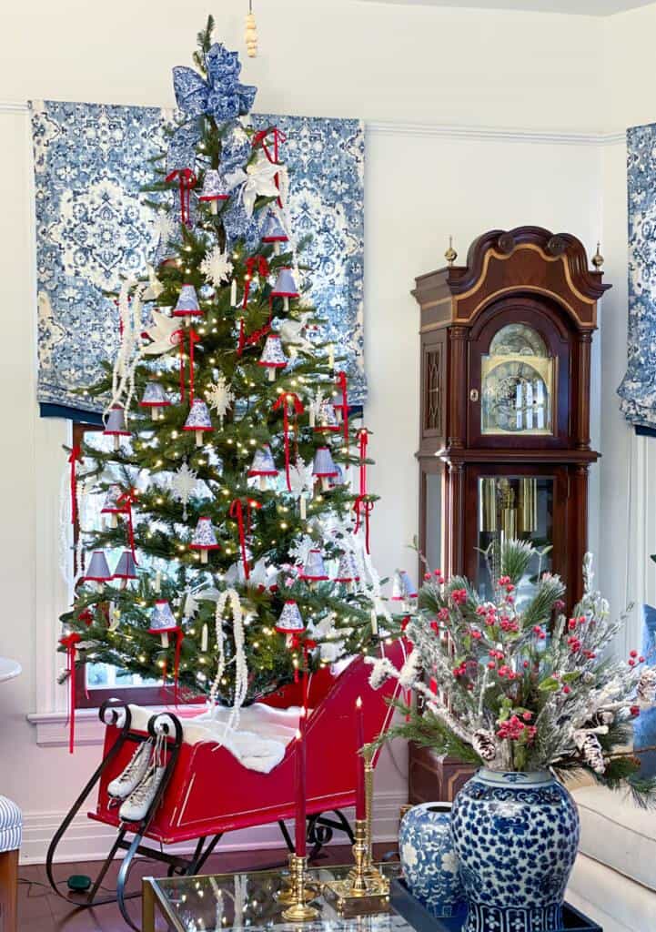 Christmas tree in the living room in a red sleigh with blue and white lamp shades for lighting.