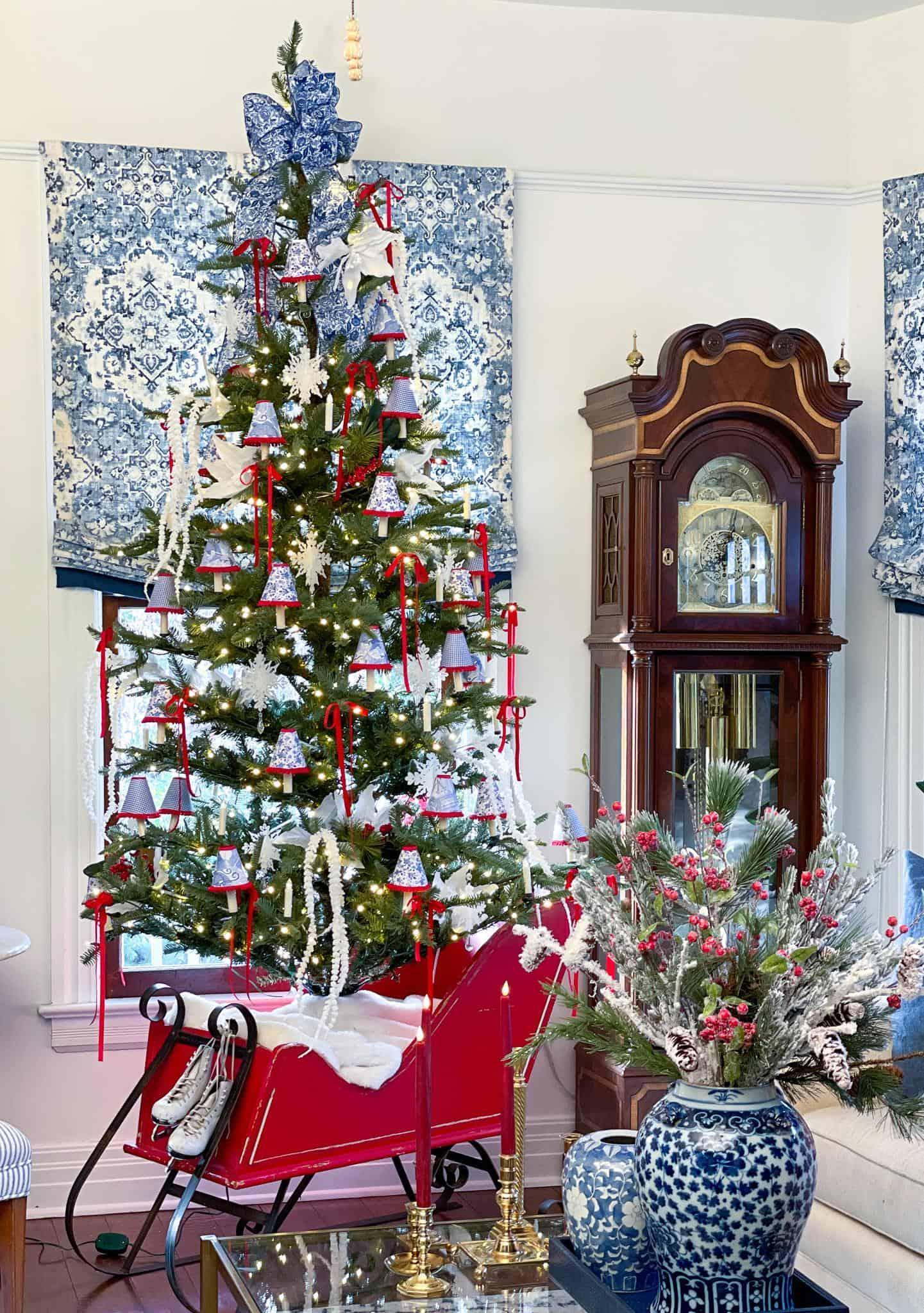 Christmas tree in the living room in a red sleigh with blue and white lamp shades for lighting.