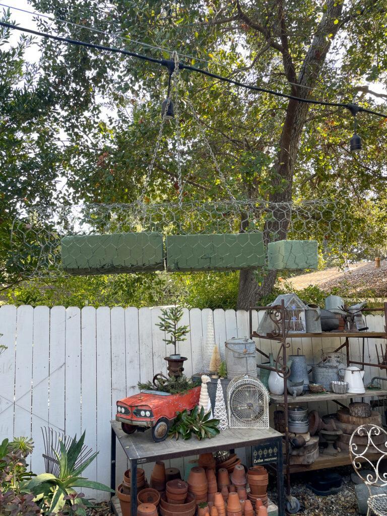 How to hang the chicken wire on the market lights ot create an outdoor chandelier with fresh greenery