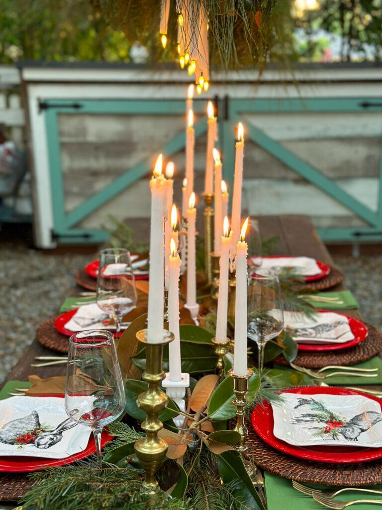 Table with candles and hanging outdoor chandelier with fresh greenery 