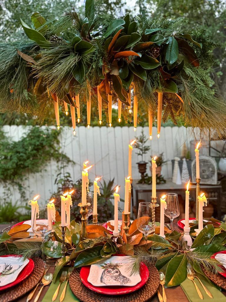 Table with outdoor chandelier  with fresh greenery and lots of beuatiful candles 