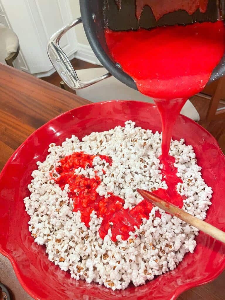 pouring the red hot candy to make  cinnamon popcorn 