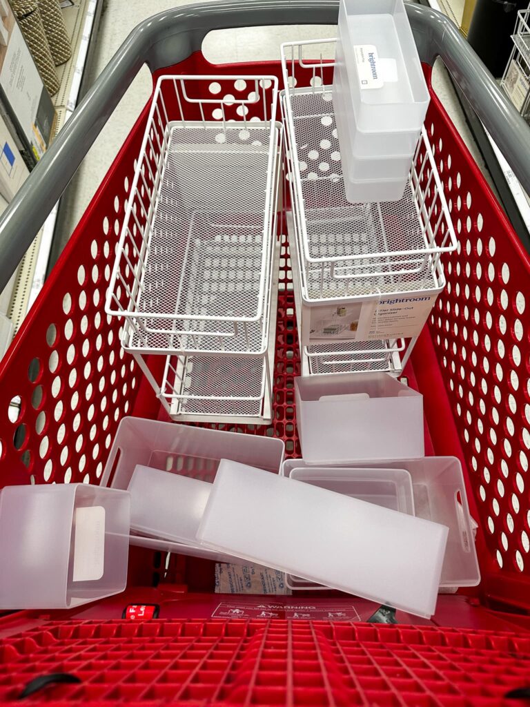 grocery cart full of organizing bins -HOW TO ORGANIZE YOUR SMALL BATHROOM CABINETS FOR A TIDY SPACE