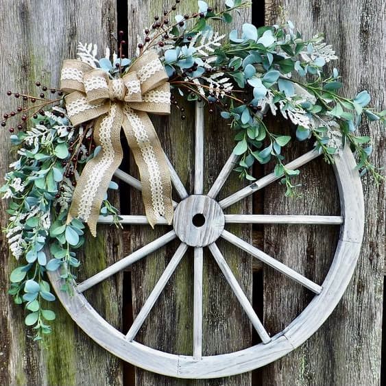 27 Unique Summer Front Door -wooden wagon wheel decorated with faux greens and a neutral bow 