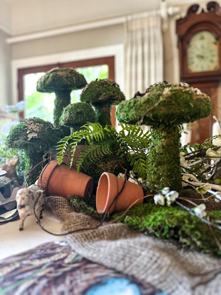 Tablescpae with moss mushrooms, flower pots, and ferns.