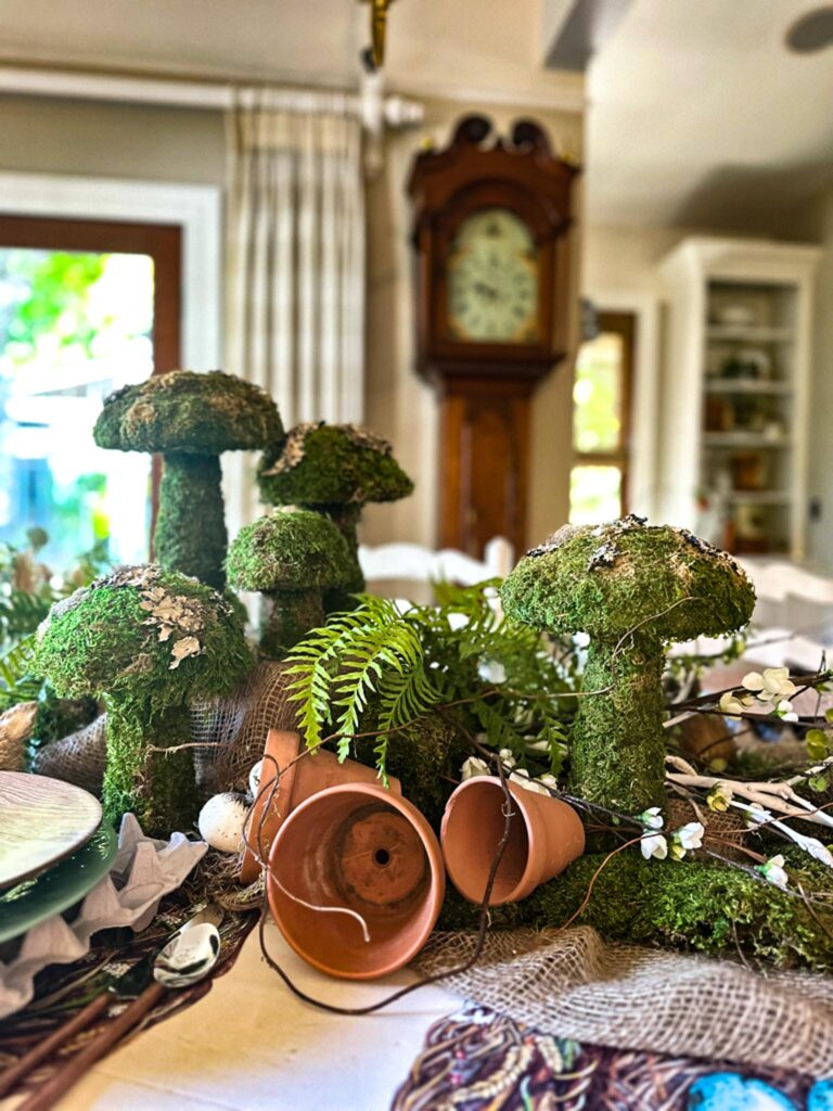 Table decorated with different size mushrooom and flower pots for spring.