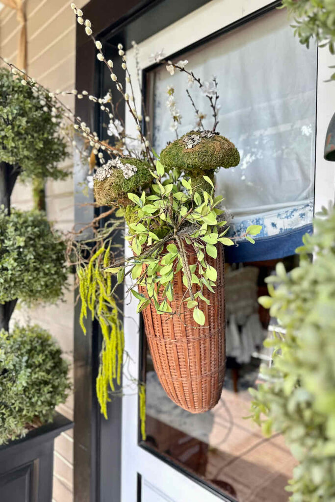 hanging basket on front door with faux greenery and moss mushrooms