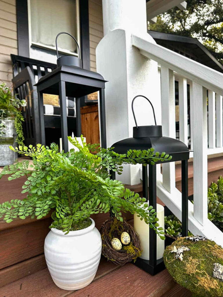 DIY spring front porch decor--solar lantern lit on the front steps of the porch. Moss mushrooms and greenery add a fresh touch to the patio.
