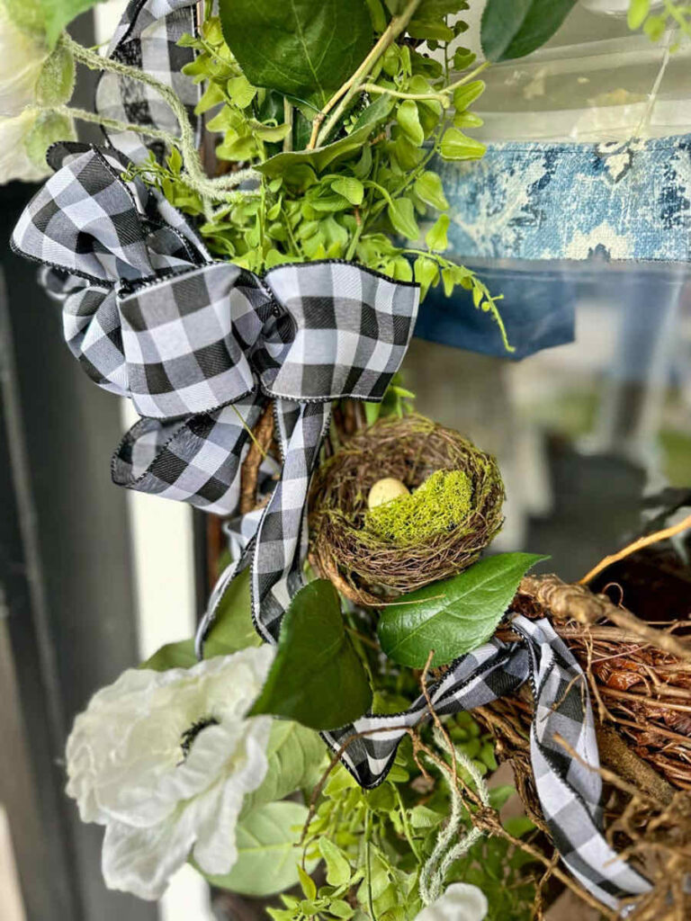 DIY spring front porch decor-Upclose image of a wreath on a door with a black and white bow.