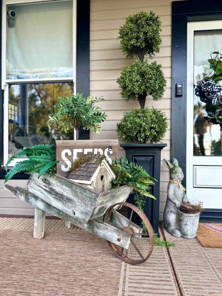 Vintage wheel barrel on front porch decorated for spring with a rabbit