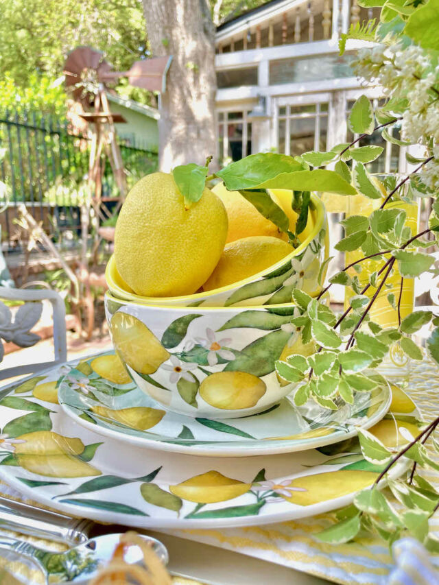 A table set with blue and dishes that have lemons on them with a bowl full of whole fresh lemons