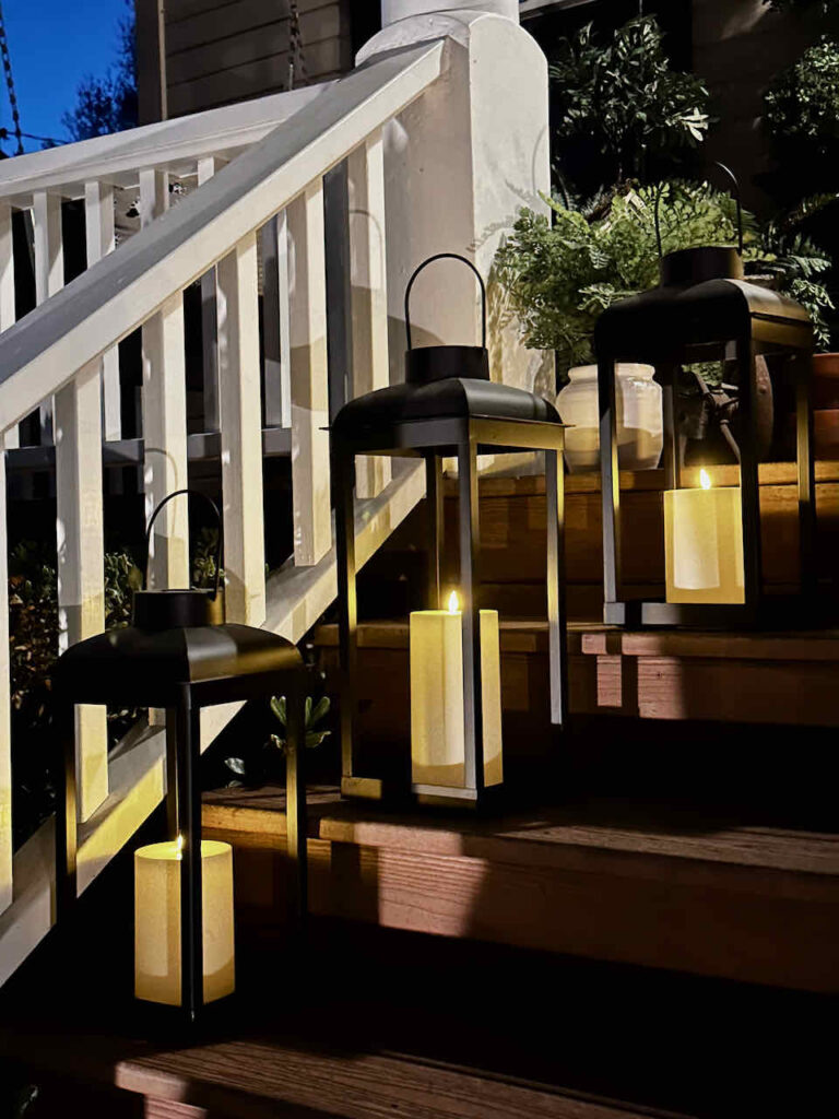 black lanterns that are solar powered lit on the frotn porch steps at night 