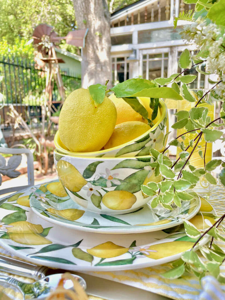 A table set with blue and dishes that have lemons on them with a bowl full of whole fresh lemons 