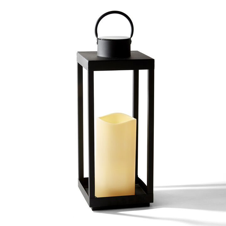 A black solar lantern with a white candle that is powered by natural energy.