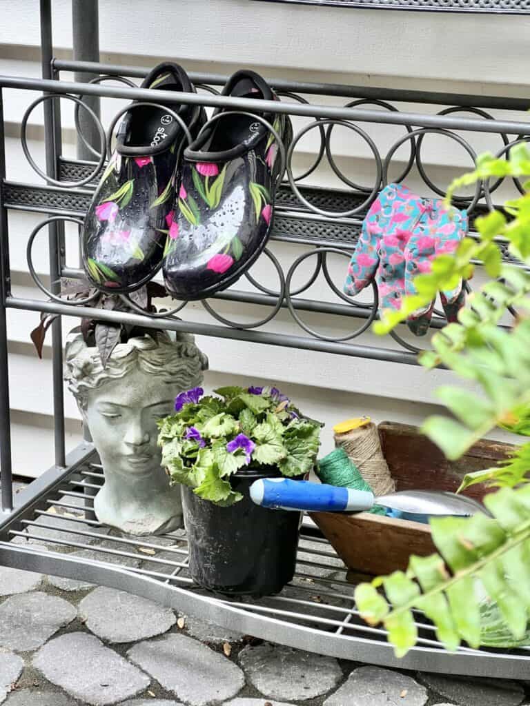 bakers rack with garden shoes and plants 