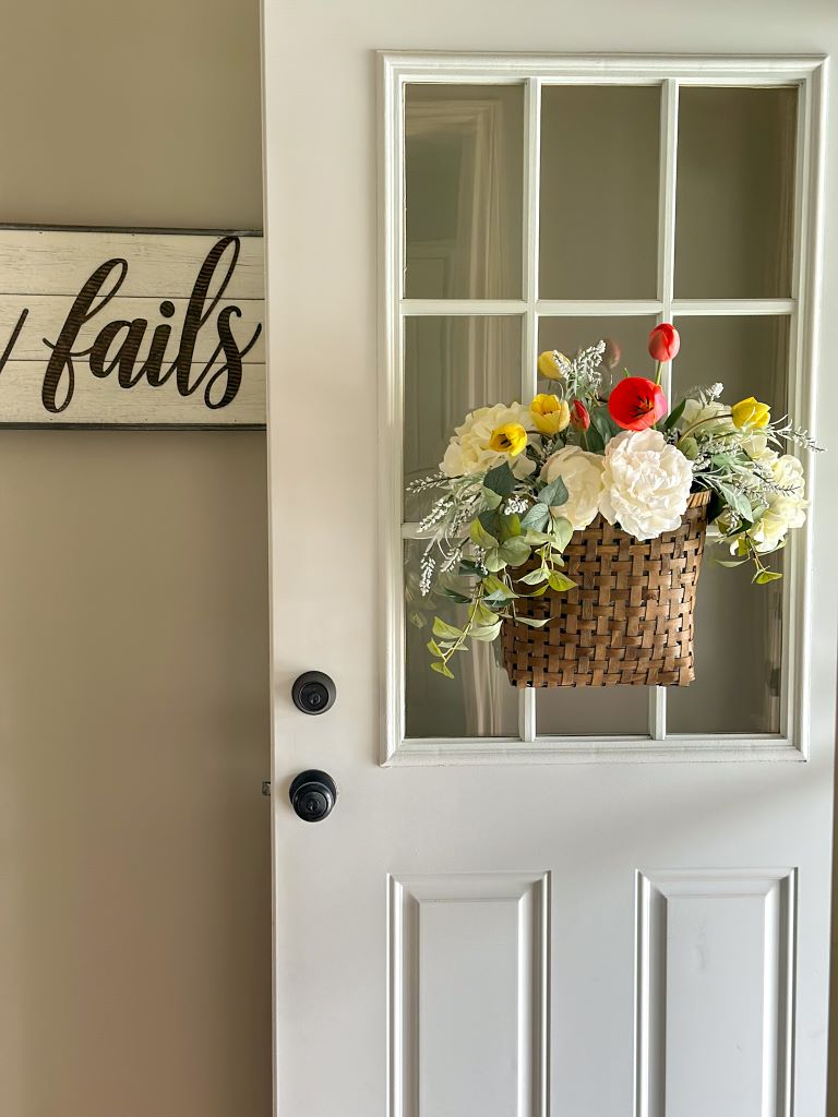 basket of flowers hanging on the door knob of a white front door 