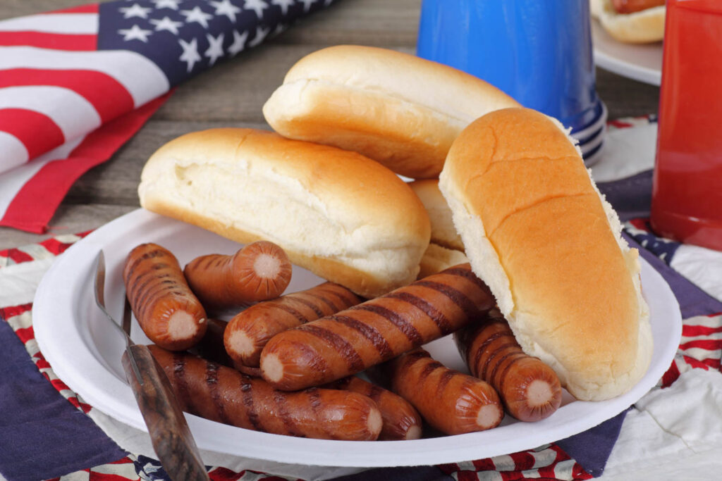 Hot dogs and buns on a plate after being grilled.