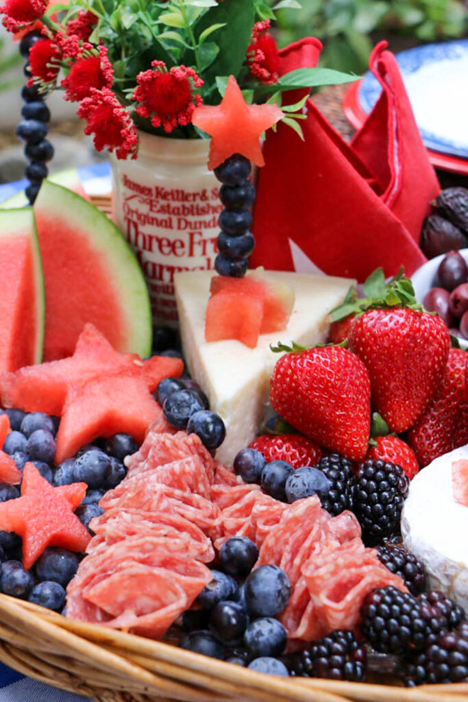 Memorial Day Party Ideas- Charcuterie basket filled with blueberries, boysenberries, brie cheese, strawberries, olives and watermelon cut in the shape of stars.