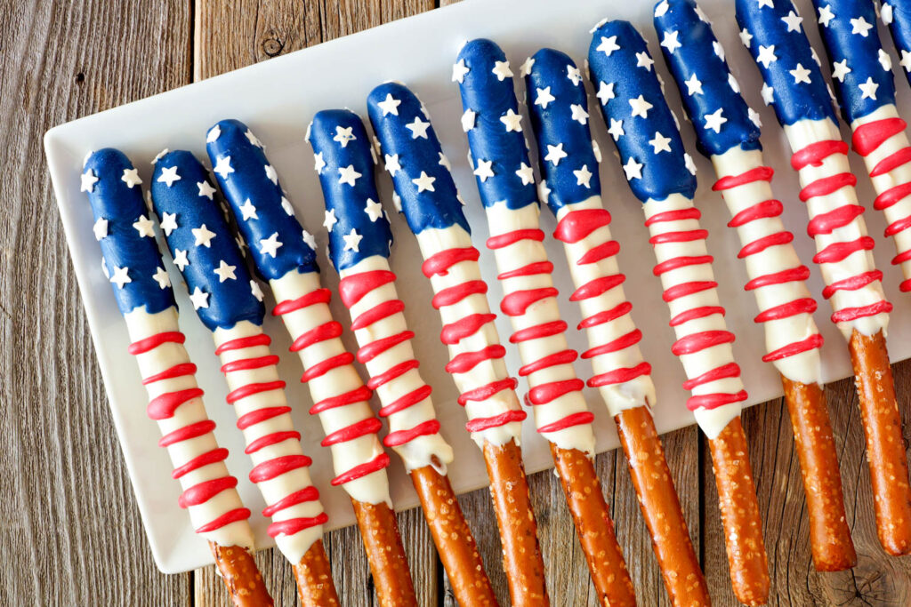 Pretzel sticks dipped in white chocolate, with blue tips with white stars and red frosting used to create stripes.