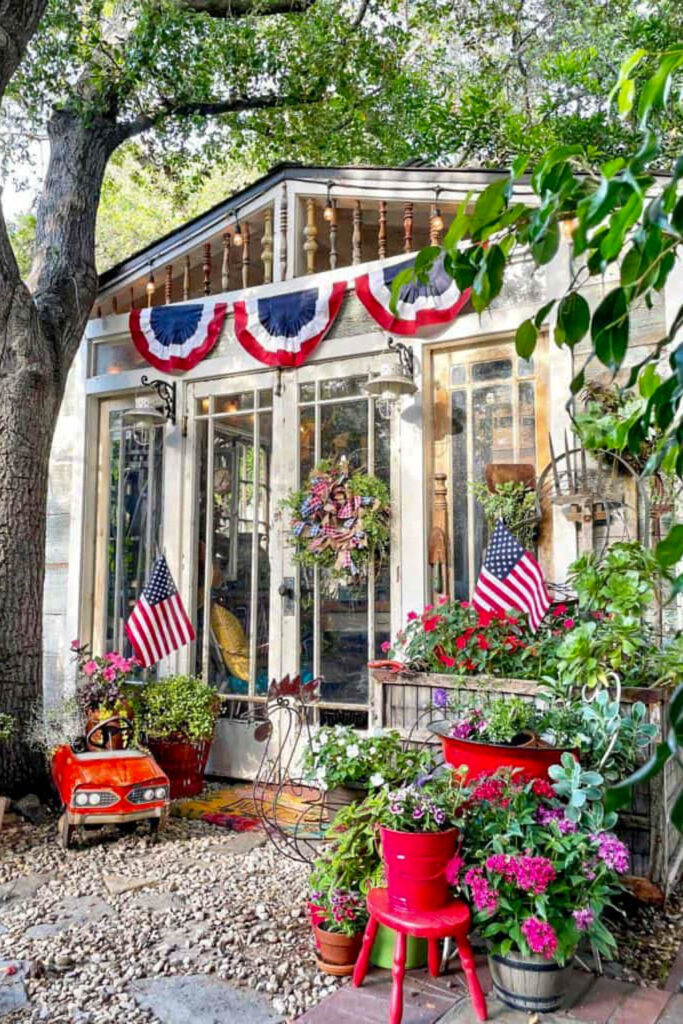 Memorial Day Party Ideas- She shed exterior decorated for Memorial day with bunting, flags, a patriotic wreath and red flowers.