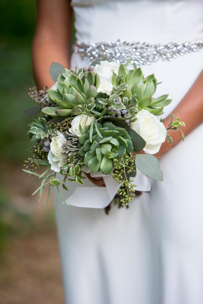 a bride in a white dress holding a bouquet of flowers and succulents 