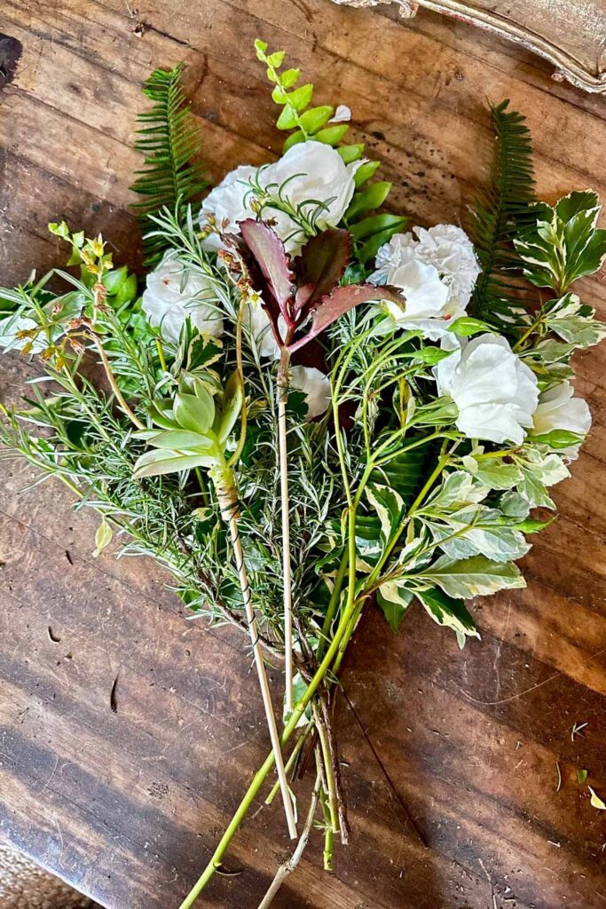 Layering greenery, roses and rosemary to create a bouquet including succulents.