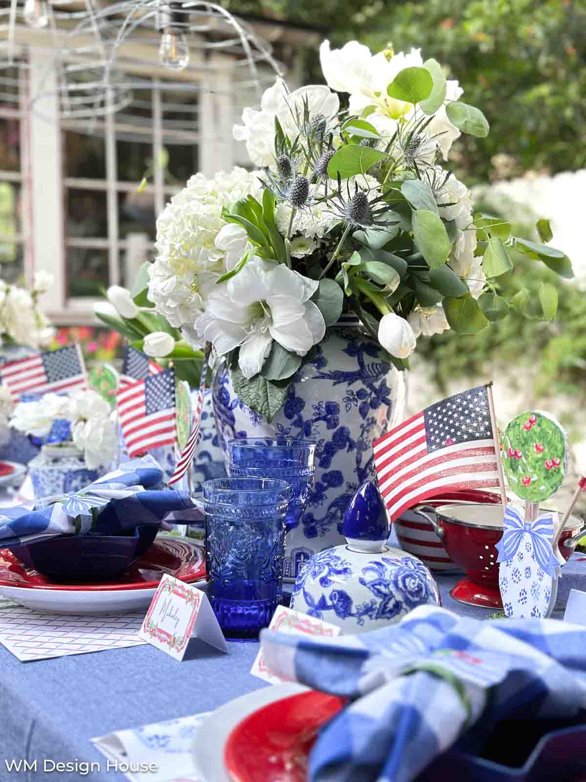 Decorating with American Flags to create a Fourth of July centerpiece with flowers in a blue and white vase 