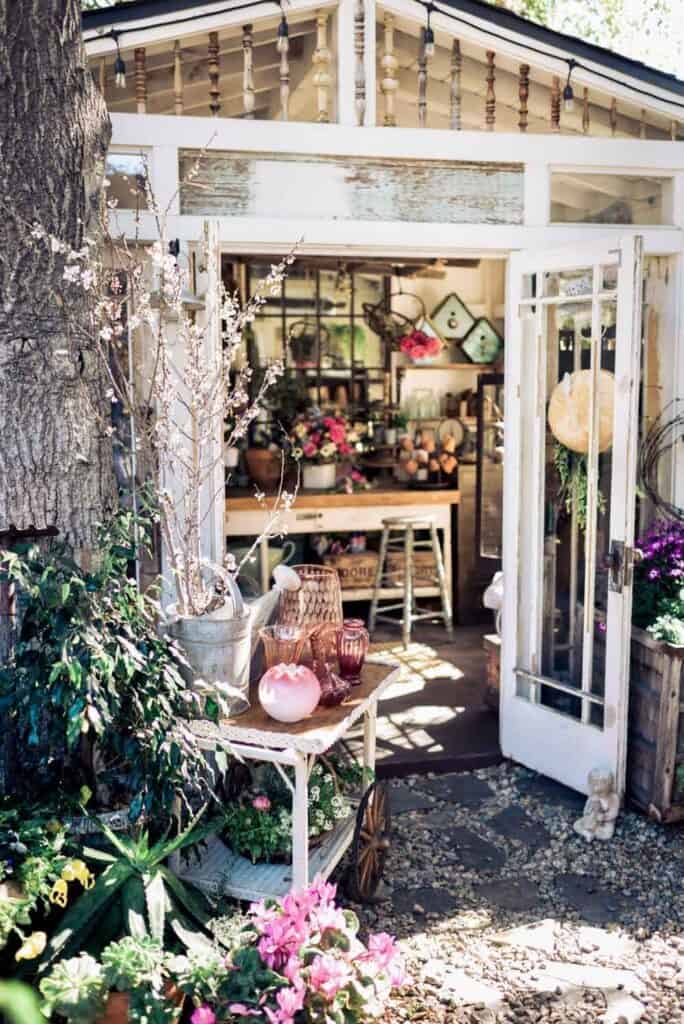 Front of she shed with the door open. Decorated with vintage garden decor indoors 