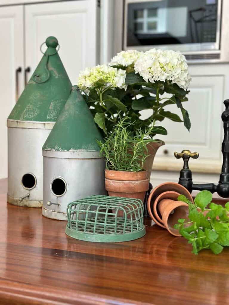 birdhouses on the kitchen counter with a vintage flower frog and clay pots